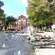 Mature trees and a large fountain with bronze statues in front of a monumental building
